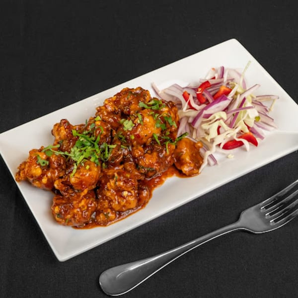 Zaika Indian Bistro Bar's chili chicken, garnished with cilantro, served with a side of red onion and cabbage salad.