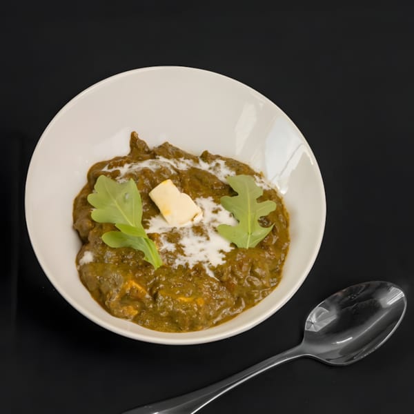 Zaika Indian Bistro Bar's Palak Paneer, a creamy green spinach and cheese curry, garnished with cream and greens.